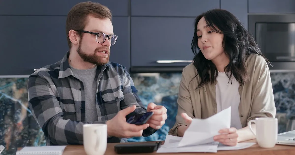 Couple at a kitchen table reviewing the cost of payday loans in Canada before applying
